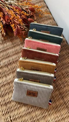 five small purses sitting on top of a wicker table next to dried flowers