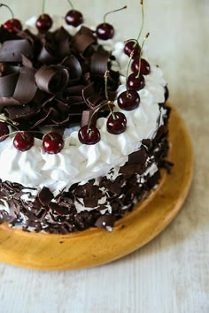 a cake with white frosting, chocolate and cherries on top