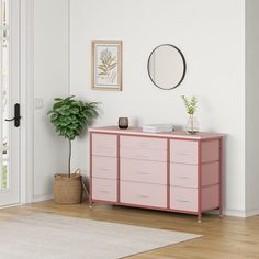 a pink dresser sitting in the corner of a room next to a potted plant