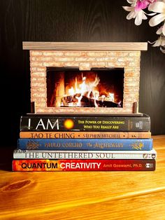 a stack of books sitting on top of a wooden table next to a fire place