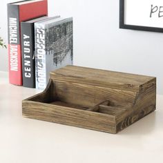 a wooden box sitting on top of a white table next to books and a plant