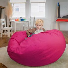 a little boy sitting on a large pink bean bag chair