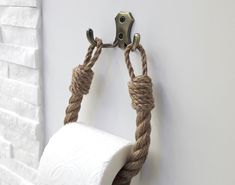 a rope wrapped around a toilet paper roll hanging on a wall next to a metal hook