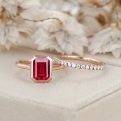 a close up of a ring with a red stone on it and white flowers in the background