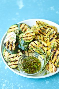 grilled zucchini and pesto on a plate with a small glass jar