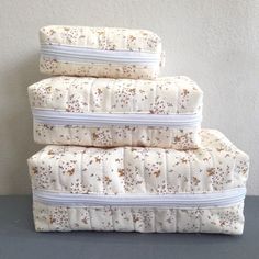 three white pillows stacked on top of each other in front of a gray wall and floor