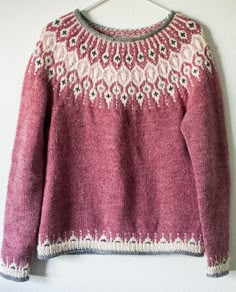 a pink sweater hanging on a white wall