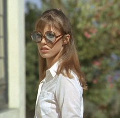 a woman wearing sunglasses standing in front of a house