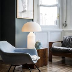 a living room with two chairs and a couch in front of large windows on the wall