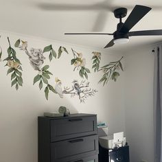 a room with a ceiling fan and wallpaper on the walls that has flowers painted on it