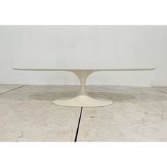 an oval white table sitting on top of a wooden floor in front of a wall