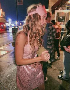 a girl in a pink dress is standing on the street