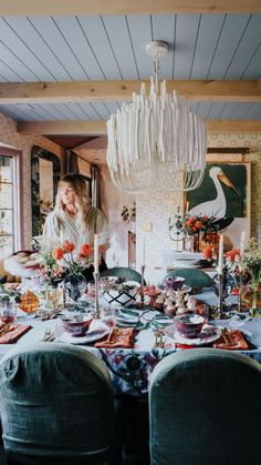 a woman standing in front of a dining room table with plates and candles on it