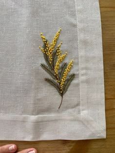 a hand is holding a piece of linen with yellow flowers on it and the fabric has been stitched together