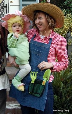 a woman holding a baby in her arms and wearing a straw hat on top of her head