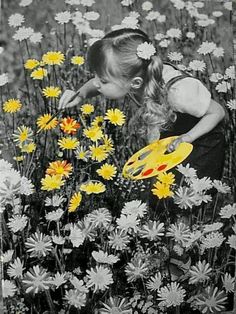 a girl picking flowers in a field with a yellow frisbee on the ground