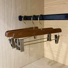 a wooden coat rack with two coats hanging from it's sides and three metal hooks on each end