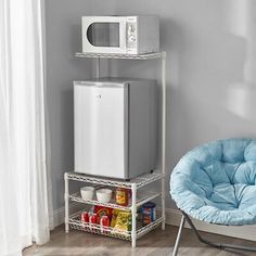 a microwave oven sitting on top of a white shelf next to a chair and table