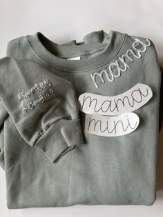 a gray shirt with the word mama on it and two pairs of shoes next to it