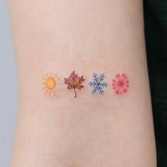 a small tattoo on the side of a woman's arm with four different colored leaves