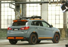 a grey car with orange trim parked in front of a camera set up for a photo shoot