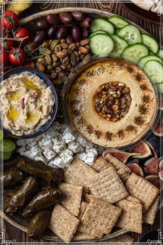 a platter filled with crackers, cucumbers, olives and other foods