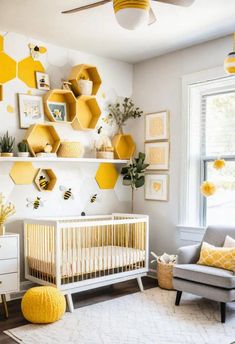 a yellow and white nursery with honeycombs on the wall, a gray chair, and a baby crib