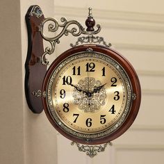 an ornate clock hanging on the side of a wall next to a doorway with white walls