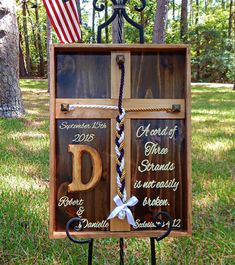 a wooden sign with rope attached to it and an american flag hanging from the back