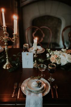 a table set for dinner with candles and flowers in the background, along with an empty place setting