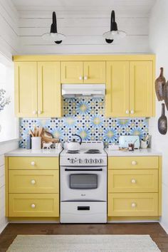 a kitchen with yellow cabinets and white stove top in the center, surrounded by hanging utensils