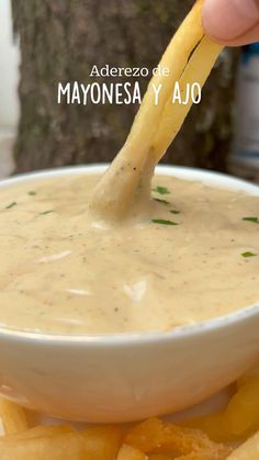 a person dipping chips into a bowl of mayonnaise with a toothpick