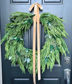 a christmas wreath on the front door of a house with a ribbon tied around it