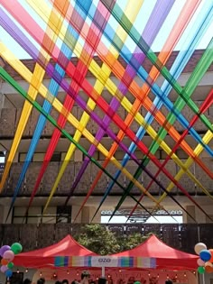 colorful streamers are hanging from the ceiling in an open area with people standing under them