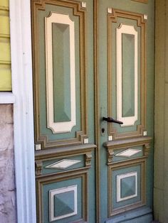 the door is painted green and has white trim on it, with an ornate design