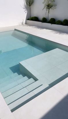 an empty swimming pool with steps leading up to the water's edge and plants growing on either side