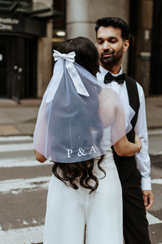 a man and woman standing next to each other under a veil on the street with buildings in the background