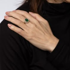 a woman's hand with a green ring on her left wrist and a white background