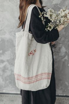 a woman carrying a white tote bag with flowers in it