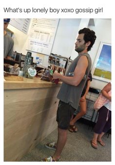 a man standing in front of a counter at a coffee shop with people behind him