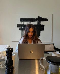 a woman sitting at a table with a laptop computer in front of her on the desk