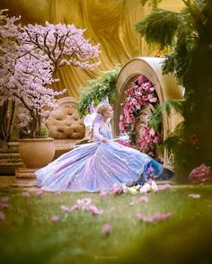 a woman in a blue dress standing next to a flower garden with pink flowers on it