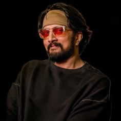 a man wearing sunglasses and a bandana on his head sitting in front of a black background