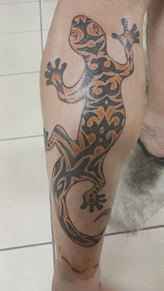 a lizard tattoo on the leg of a person with tile flooring in the background