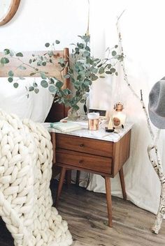 a bed room with a wooden nightstand and a white blanket on top of the bed