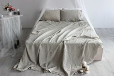 an unmade bed with white sheets and pillows on the floor next to a night stand