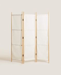 three panel folding screen in natural wood with white linen linings on the sides and bottom panels