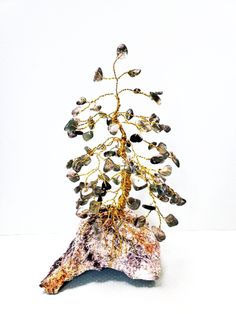 Custom Order Wire Pine Gem Tree Your gem tree will be similar to the photos shown, in structure and size only (as rock bases are all truly unique!). All branches contain real semi-precious gems, and are all wire wrapped. These wire sculpture make excellent gifts for yourself, family & friends! Pine Tree Stats: Average size: 7-8 inches tall and 4-6 inches wide Average # of Branches: 27 branches  Average # of Gems: 110 gems  Here are the steps to creating your own custom gem tree order: Step 1: Color and/or Type of Gem.  Here are some of the most popular gemstones: BLACK: Onyx, Jasper, Obsidian, Tourmaline BROWN: Crysanthemum Stone, Bronzite GREY: Labradorite, Botswana Agate PURPLE: Amethyst, Ametrine BLUE: Aventurine, Lapis Lazuli, Sodalite, Quartzite, Chrysocolla, Apatite GREEN: Aventurine Sculpture Nature, Healing Tree, Crystal Trees, Gem Tree, Zen Home Decor, Tree Of Life Art, Types Of Gems, Wire Tree Sculpture, Wire Trees