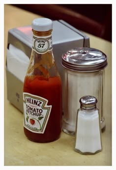 a bottle of heinzz tomato sauce next to a salt and pepper shaker on a table