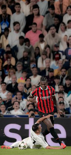 two soccer players colliding for the ball in front of an audience at a sporting event